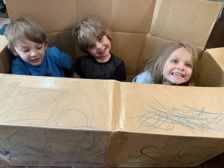 Three June Lake kids laughing inside a cardboard fort