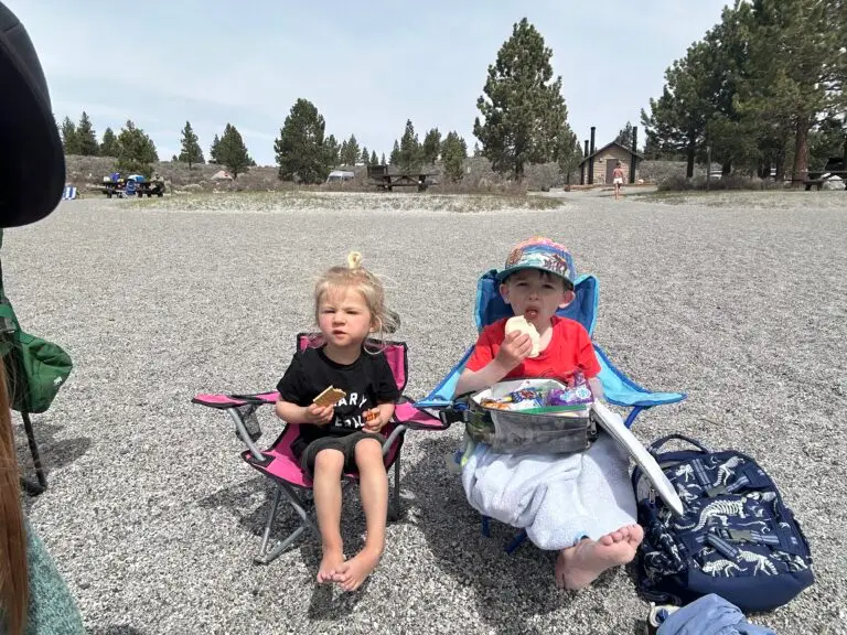 Two kids having a snack in camp chairs at a June Lake campground
